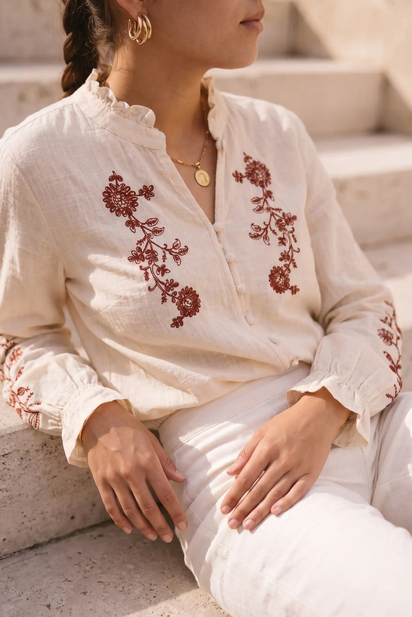 Blusa blanca con bordado floral rojo, manga larga y cuello fruncido, ideal para looks boho y verano.