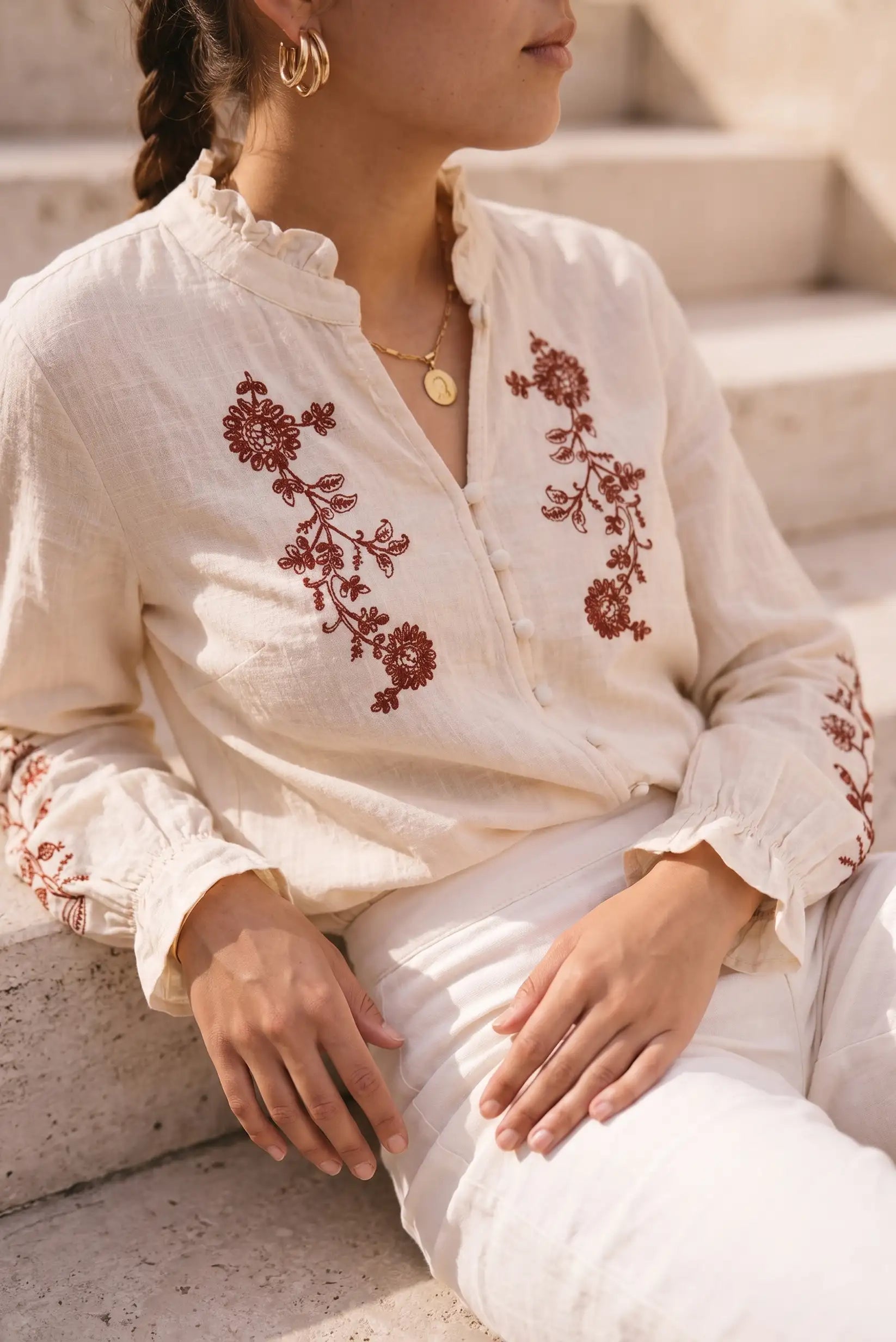 Blusa blanca con bordado floral rojo, manga larga y cuello fruncido, ideal para looks boho y verano.