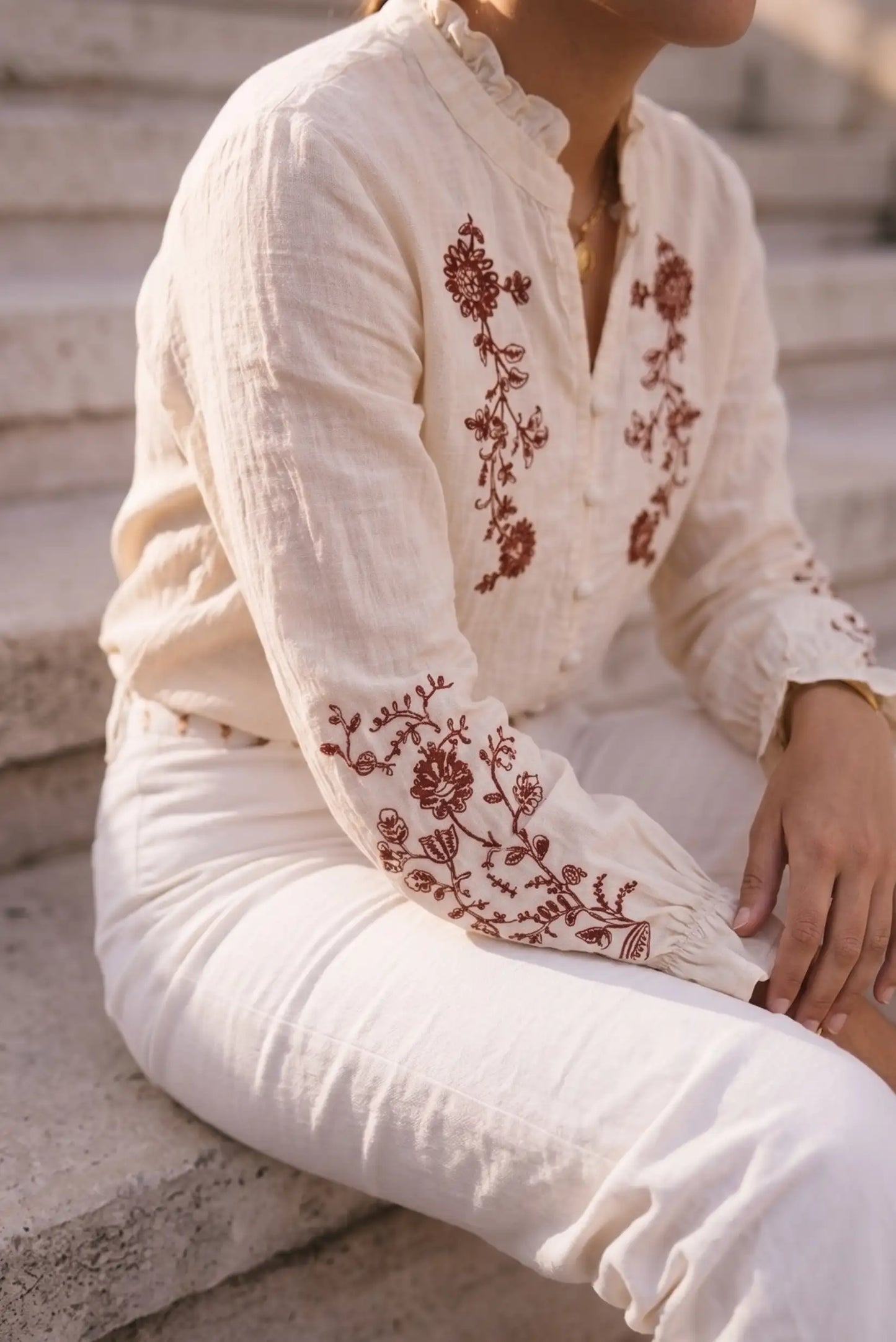 Blusa blanca con bordado floral en mangas y pecho, estilo boho, ideal para looks femeninos y cómodos.