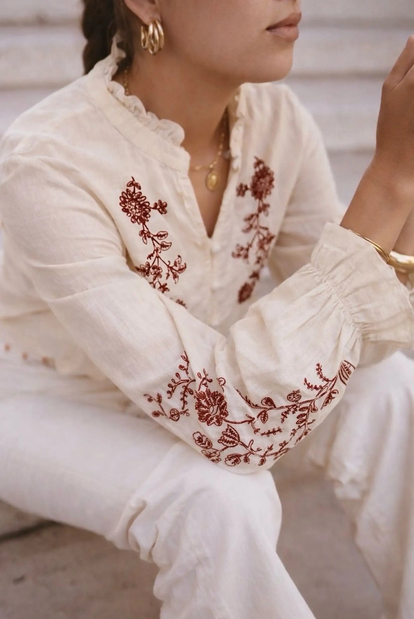 Blusa blanca con bordado floral rojo, mangas abullonadas y cuello fruncido, ideal para looks boho y elegantes.