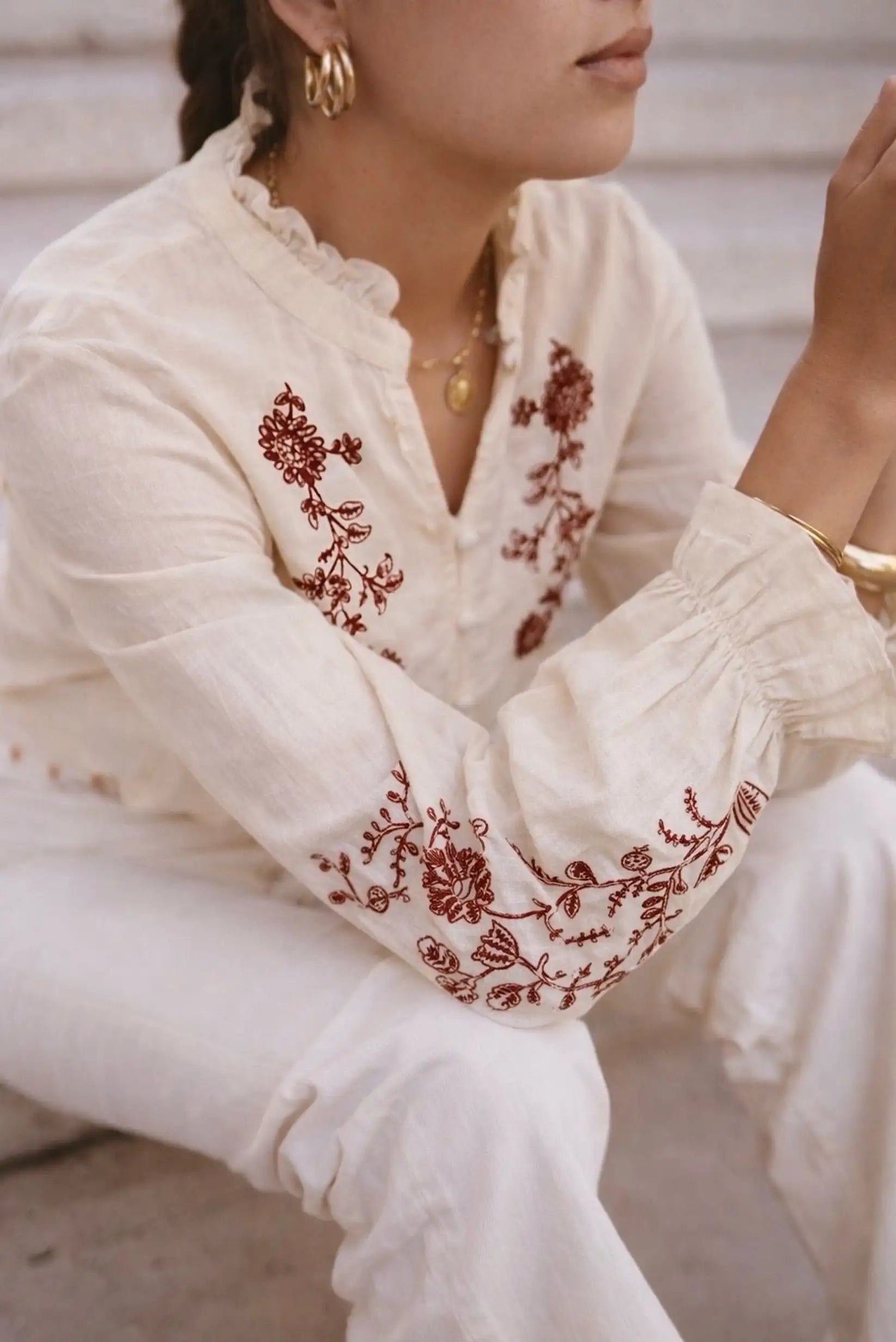 Blusa blanca con bordado floral rojo, mangas abullonadas y cuello fruncido, ideal para looks boho y elegantes.