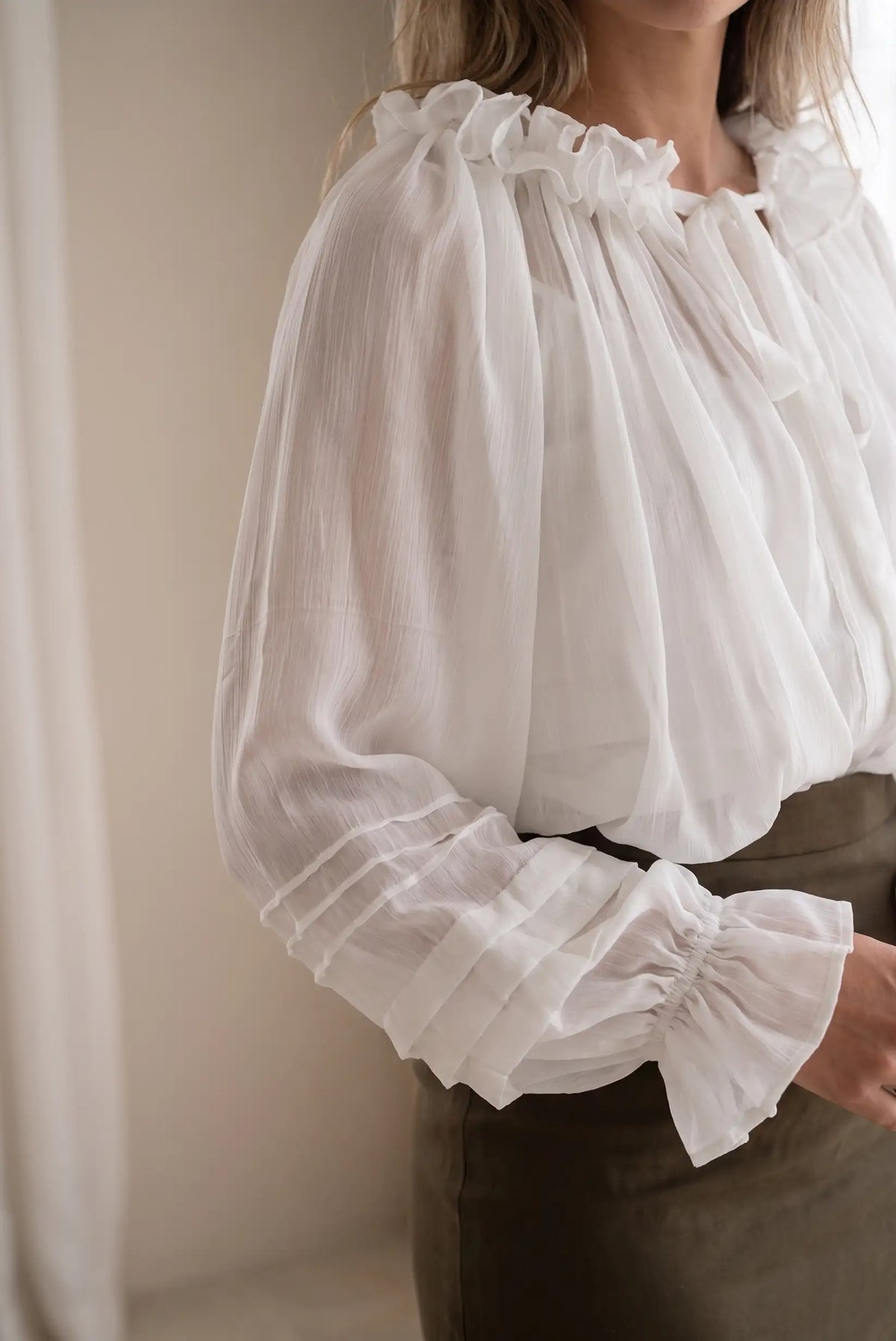 Blusa blanca de gasa con volantes en el cuello y puños elásticos fruncidos