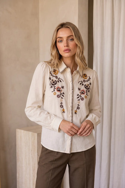 Mujer vistiendo camisa beige de manga larga con bordados florales de CHICA del Sur.