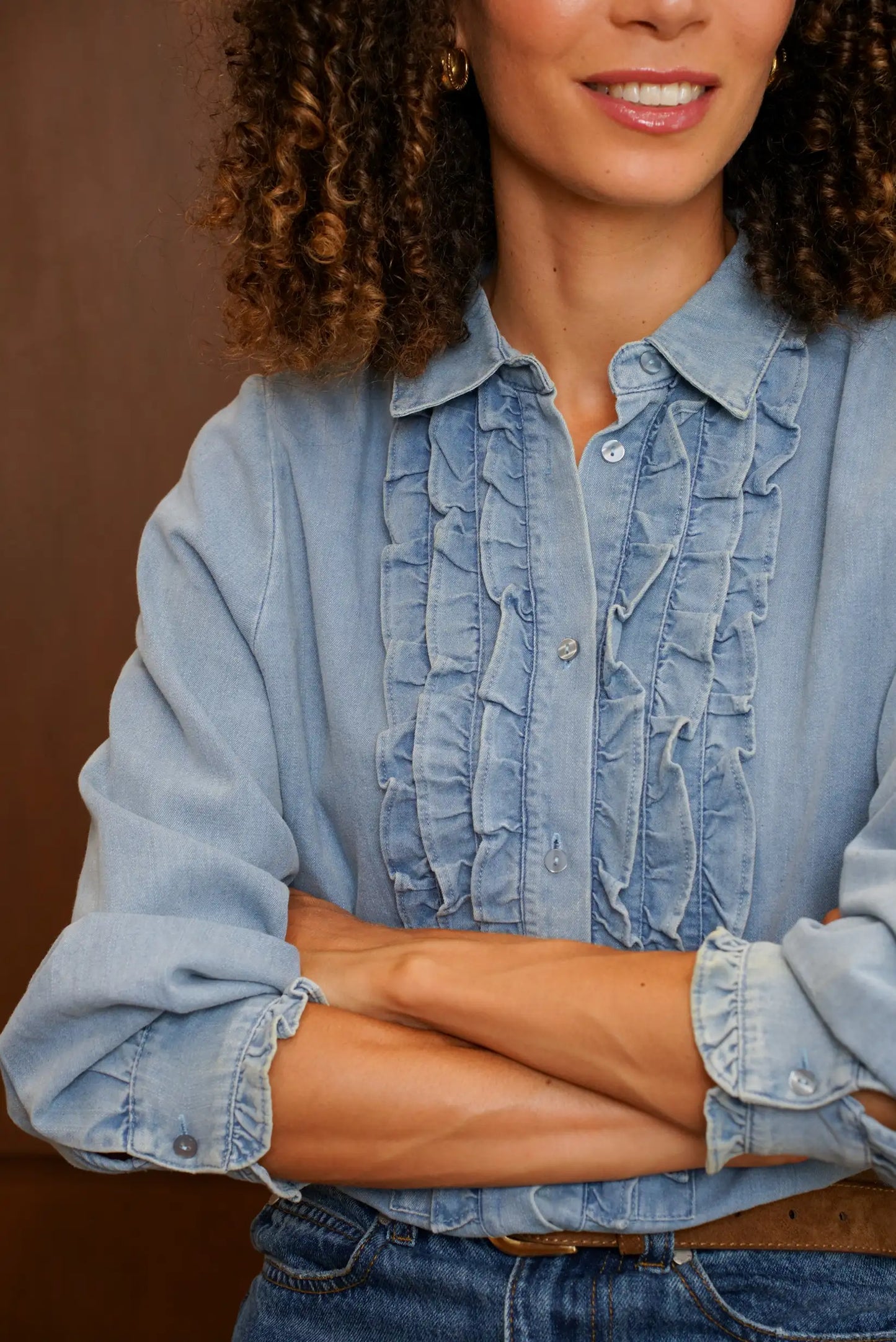 Mujer vistiendo camisa de denim azul claro con volantes frontales y botones