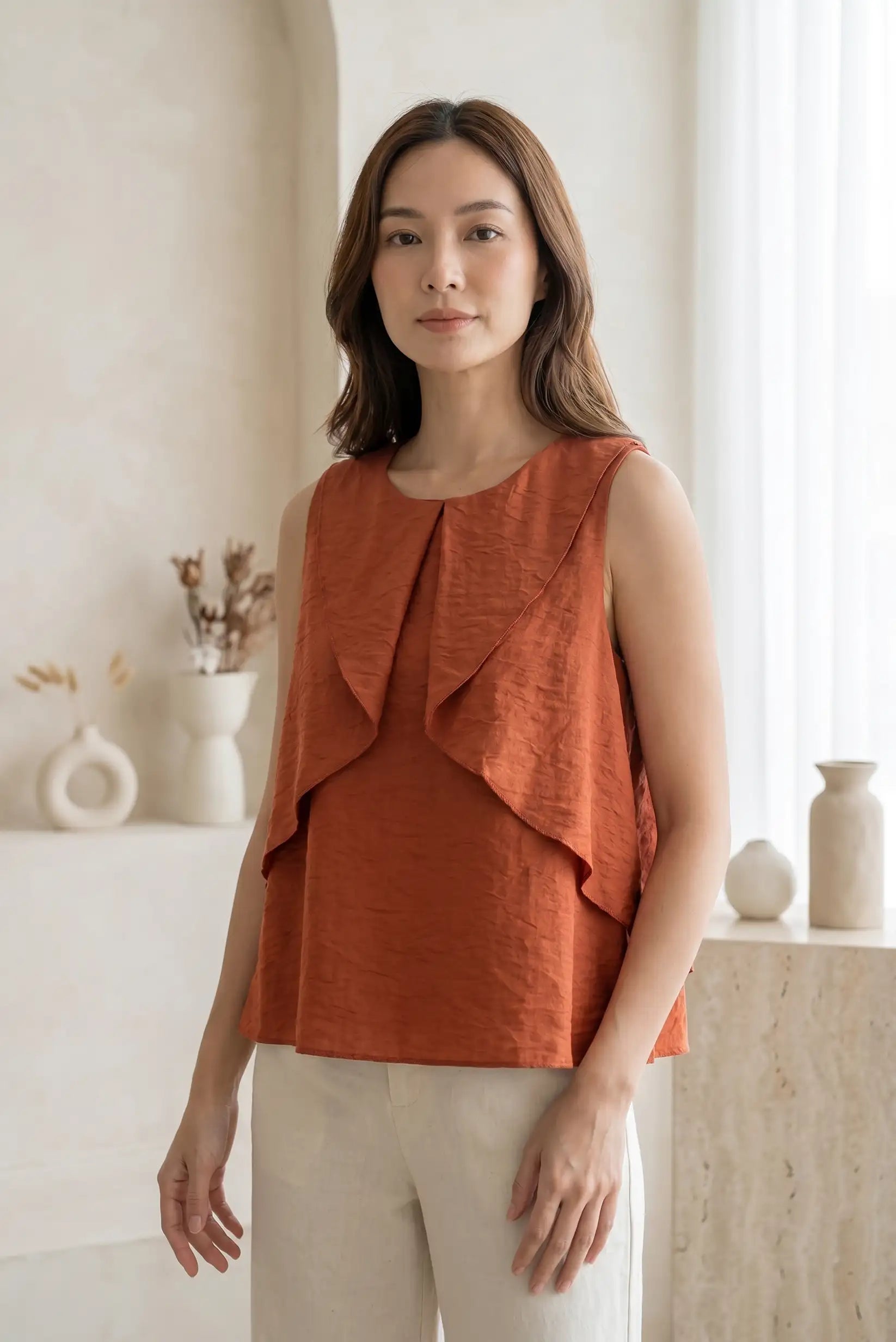 Mujer con blusa sin mangas teja y volantes, look de primavera casual elegante