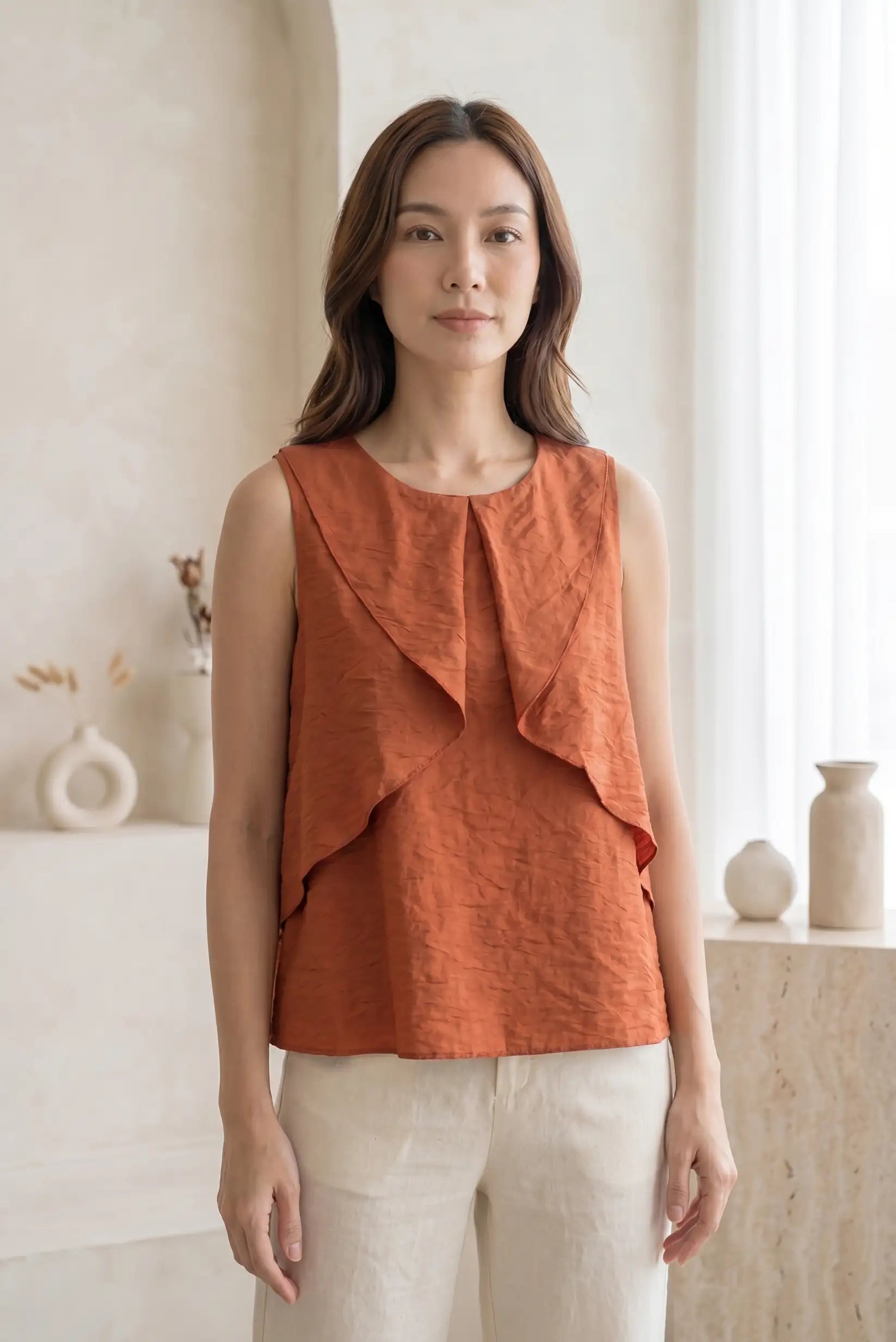 Mujer con camisa sin mangas teja con volantes, look casual de primavera en interior luminoso