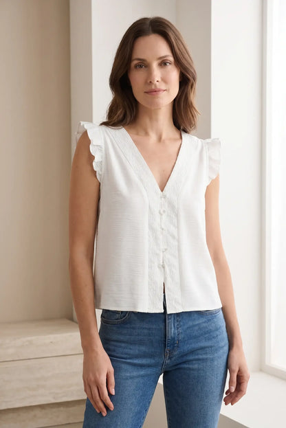 Mujer con blusa blanca sin mangas y volantes, escote en V, look casual de verano