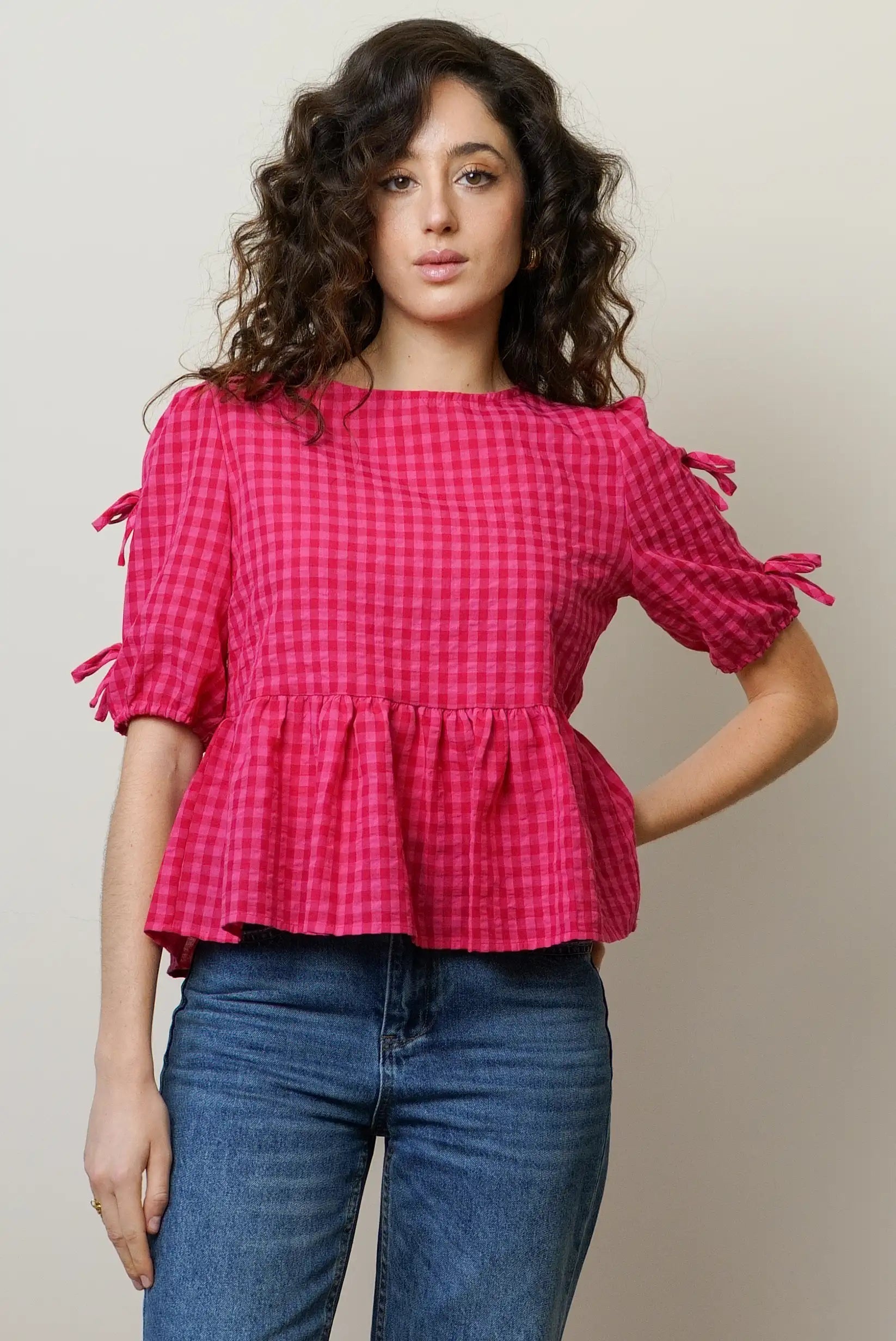 Camisa de mujer rosa con manga corta y cuadros, lazo en las mangas y corte peplum.