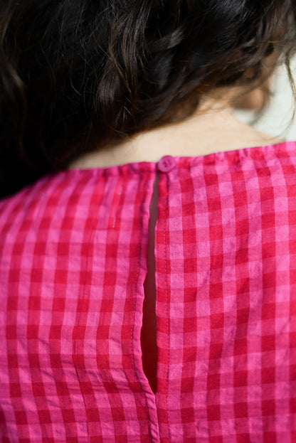 Detalle de la espalda de camisa rosa de cuadros con botón y abertura en la nuca, moda casual mujer