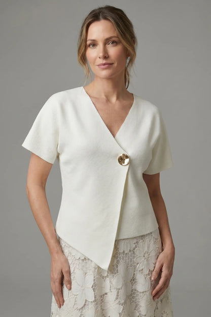 Mujer con camisa blanca cruzada de manga corta y botón dorado, falda de encaje floral.