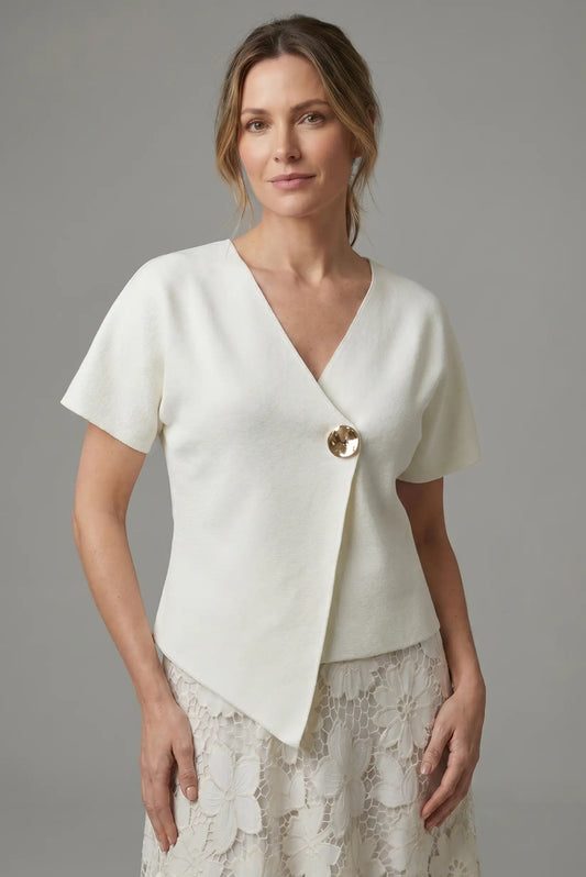 Mujer con camisa blanca cruzada de manga corta y botón dorado, falda de encaje floral.