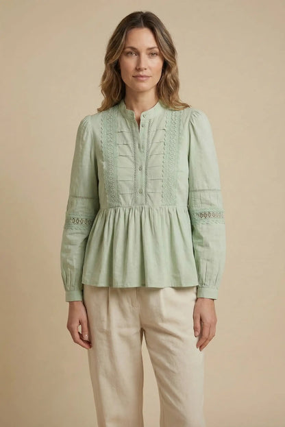 Mujer con camisa verde agua de manga larga y detalles de encaje, look primaveral casual