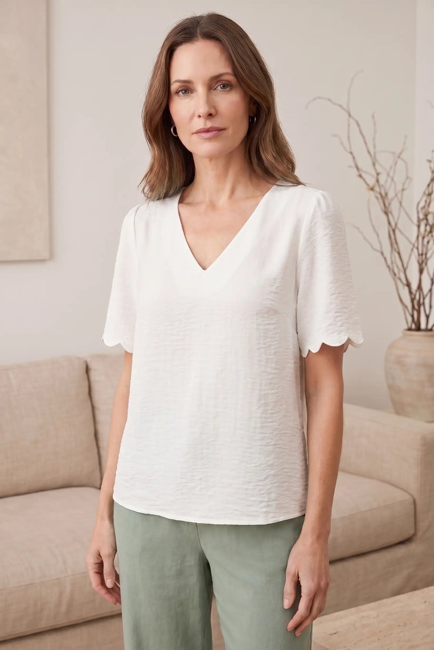 Blusa blanca con cuello en V y mangas cortas con detalle de volante, ideal para looks casuales y estilosos.