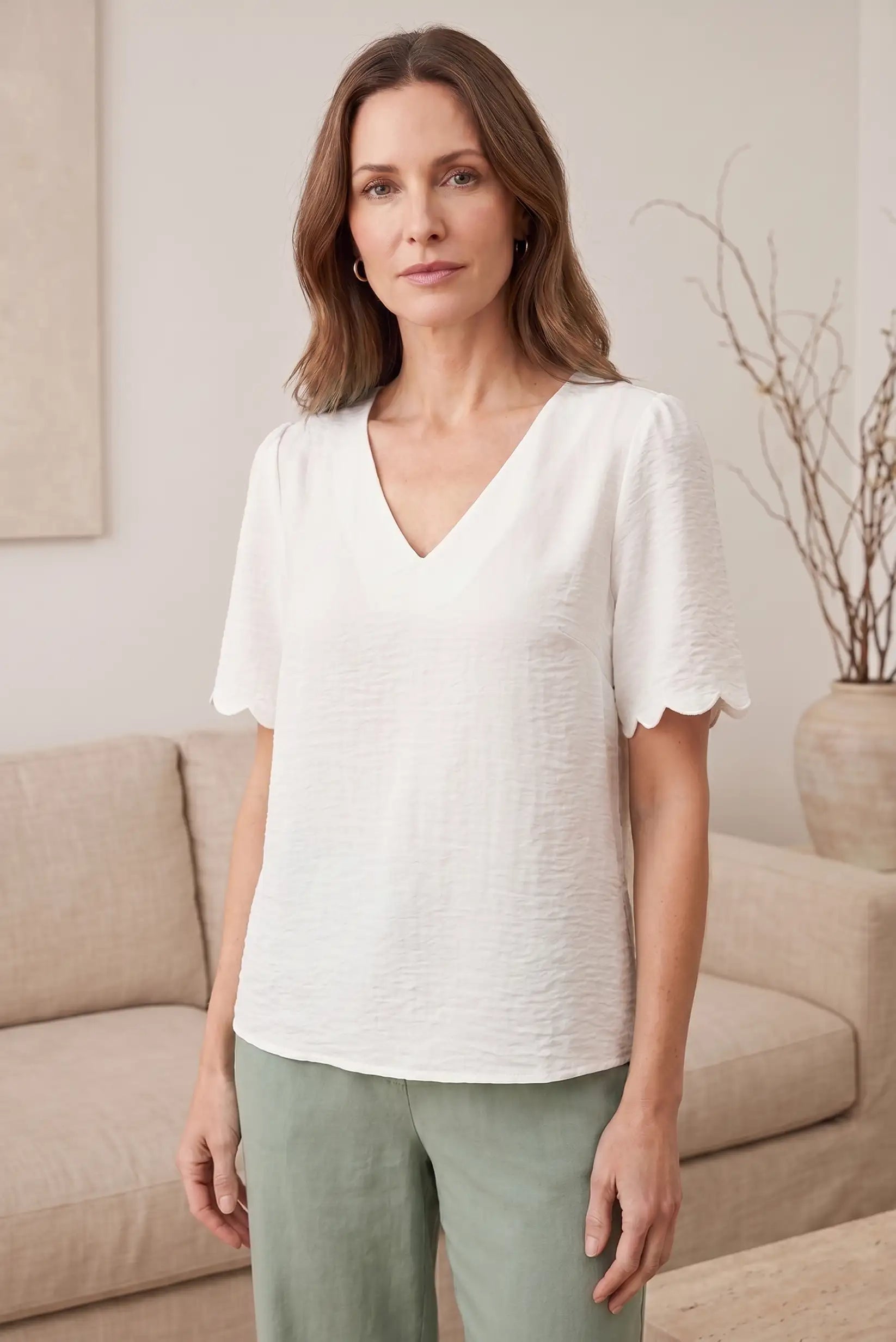 Blusa blanca con cuello en V y mangas cortas con detalle de volante, ideal para looks casuales y estilosos.