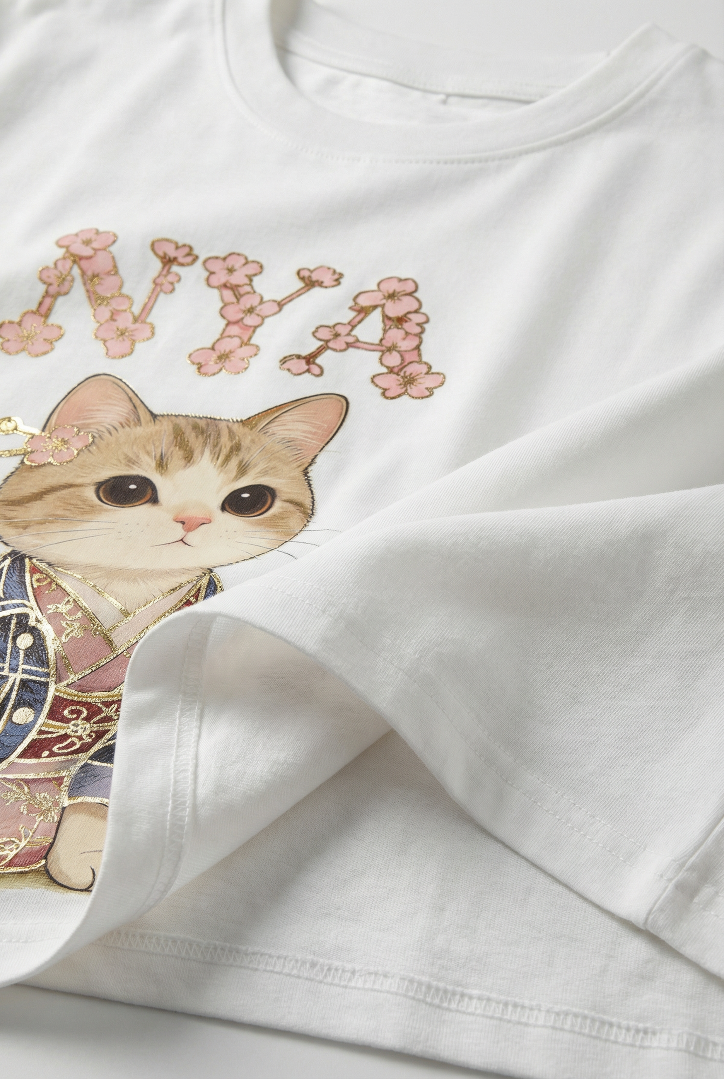 Camiseta blanca de mujer con estampado de gato y flores rosas, estilo casual femenino.