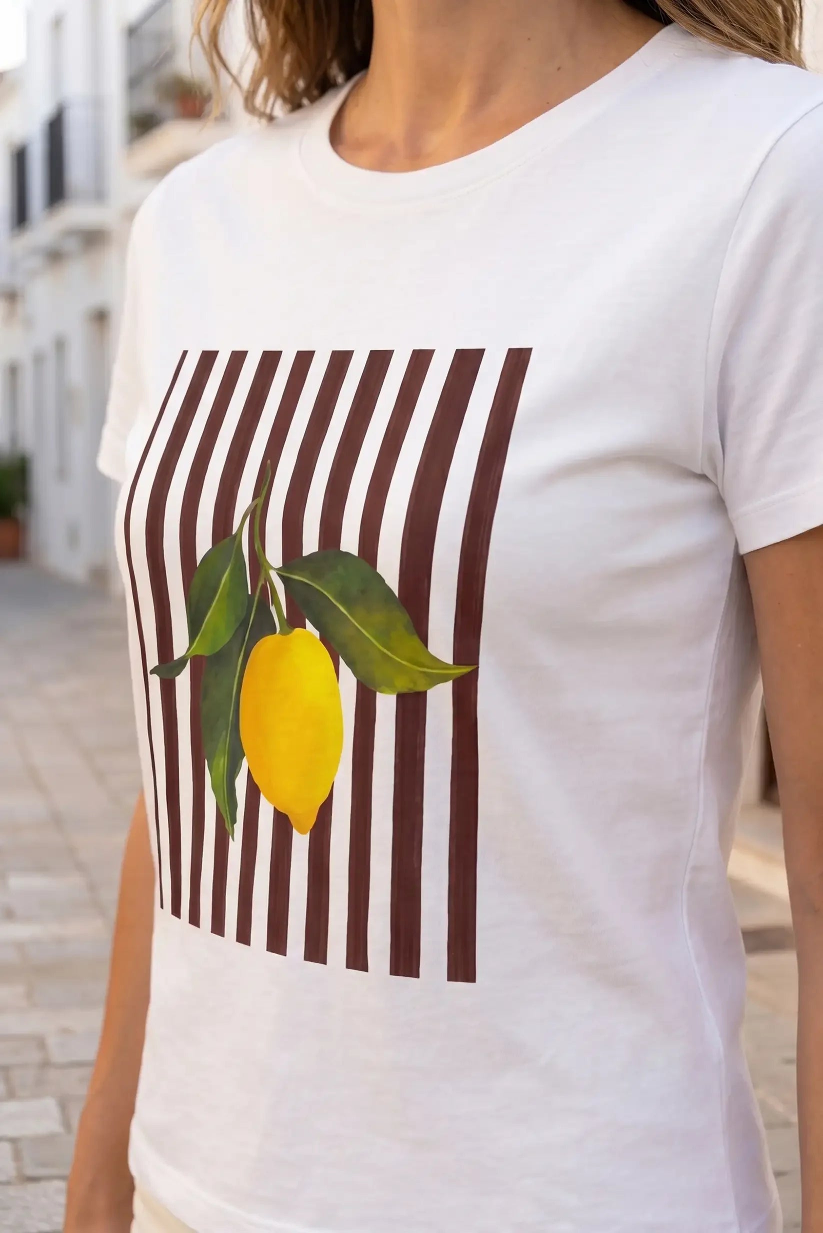 Camiseta blanca con estampado de limón y rayas marrones, ideal para looks casuales y estilosos.