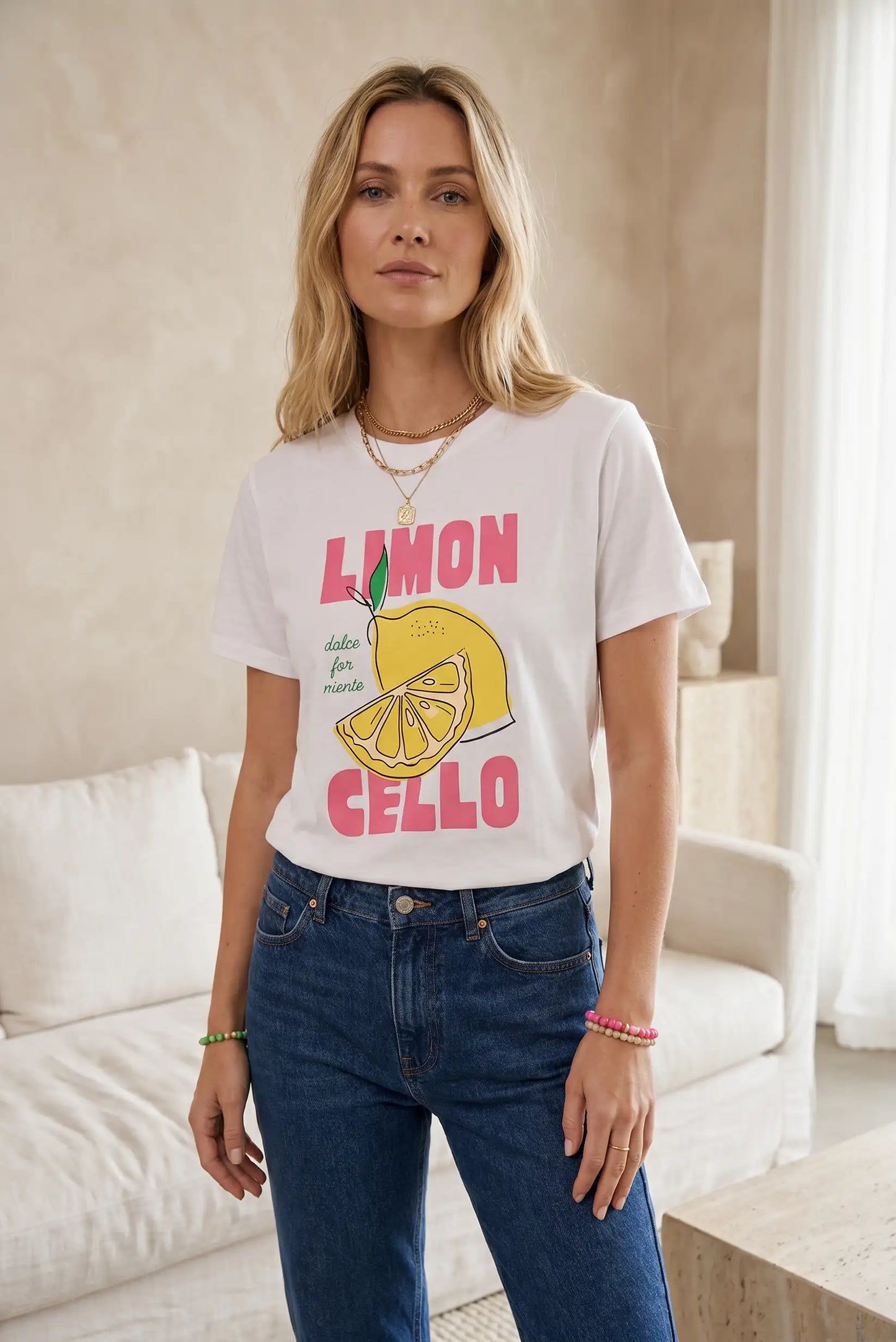 Camiseta blanca de mujer con dibujo de limón y letras rosas, combinada con jeans azules.