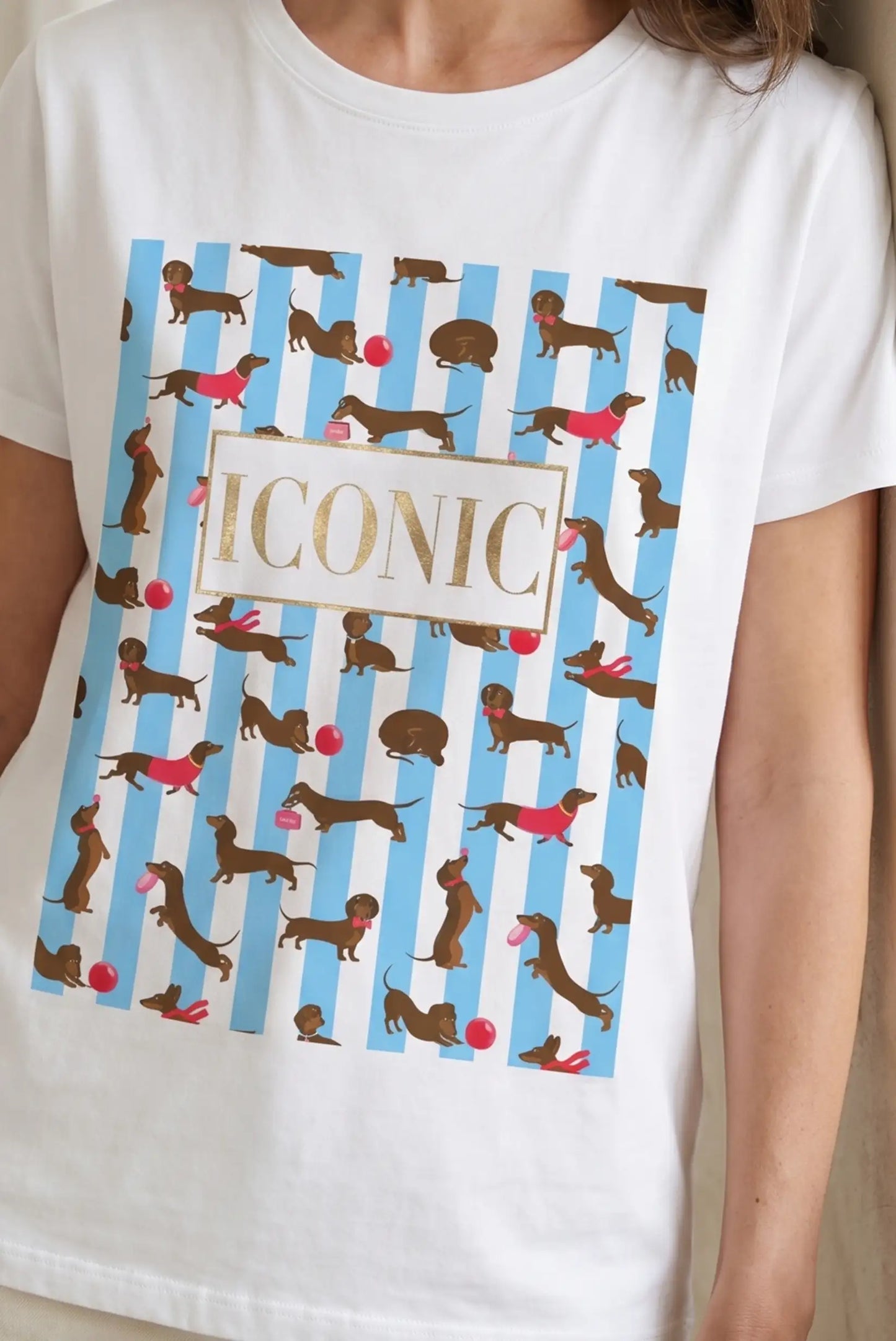 Camiseta blanca de mujer con rayas azules y estampado de perros salchicha, texto ICONIC.