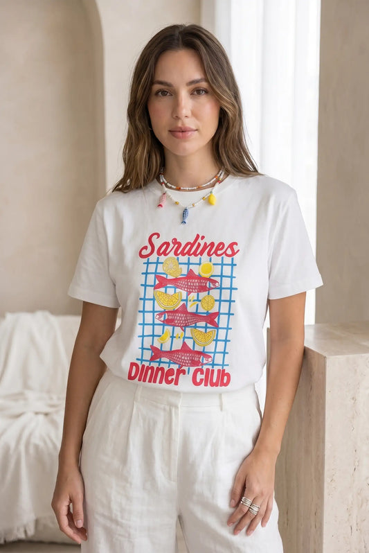 Mujer con camiseta blanca de manga corta estampada con sardinas y limones, pantalón claro