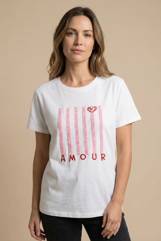 Mujer con camiseta blanca de algodón, diseño líneas rosas y texto 'AMOUR', moda casual femenina.