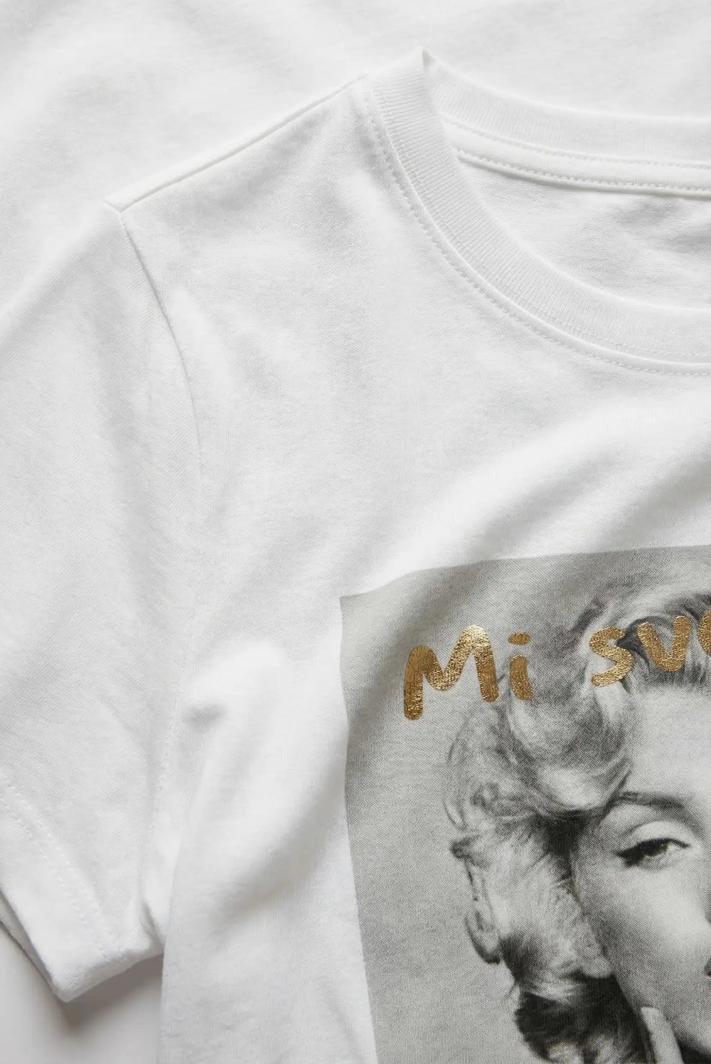 Camiseta blanca mujer con estampado artístico en gris y letras doradas, estilo casual.