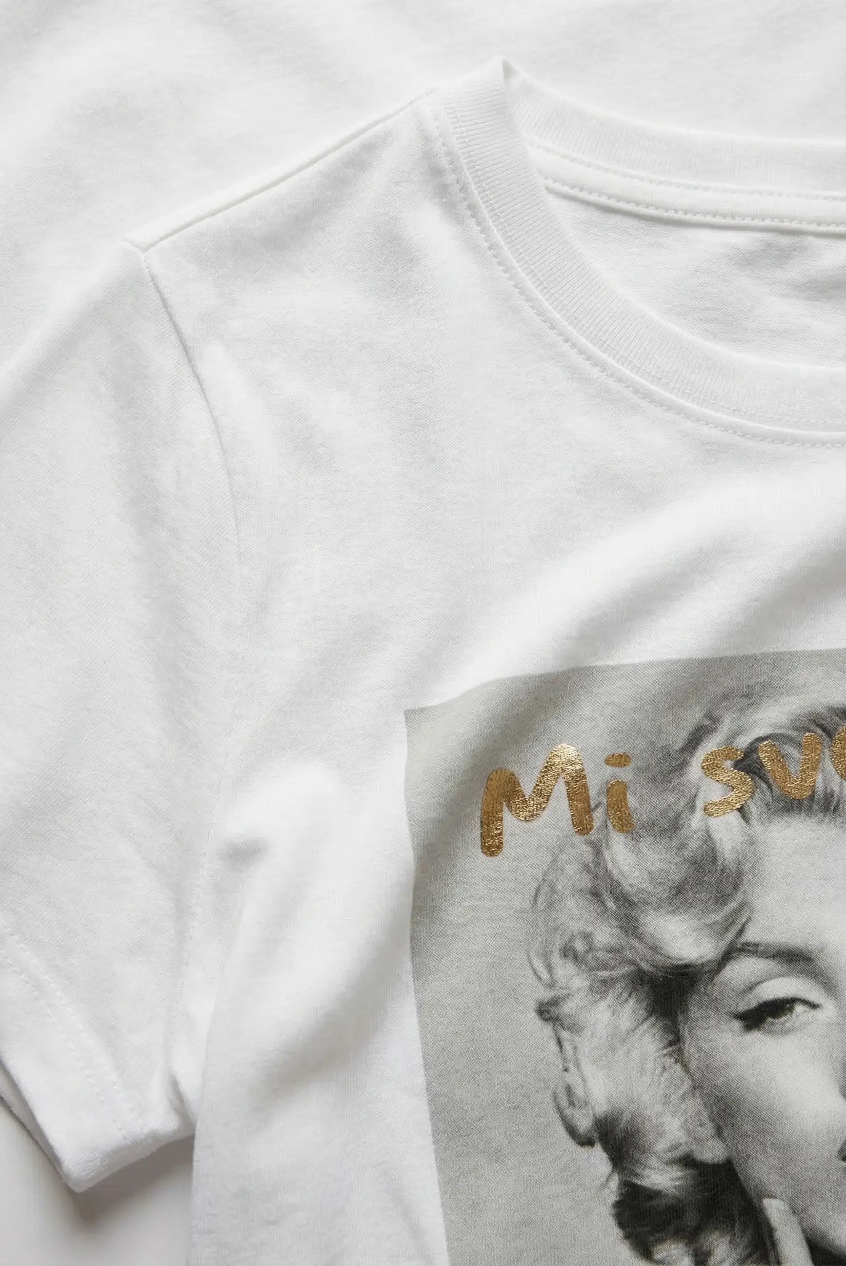 Camiseta blanca mujer con estampado artístico en gris y letras doradas, estilo casual.