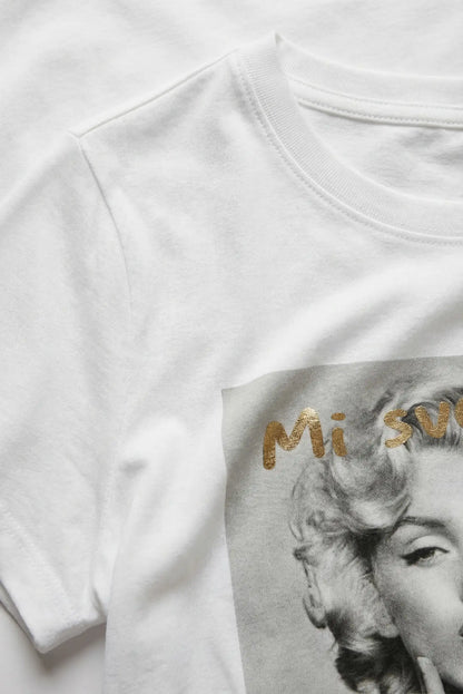 Camiseta blanca mujer con estampado artístico en gris y letras doradas, estilo casual.