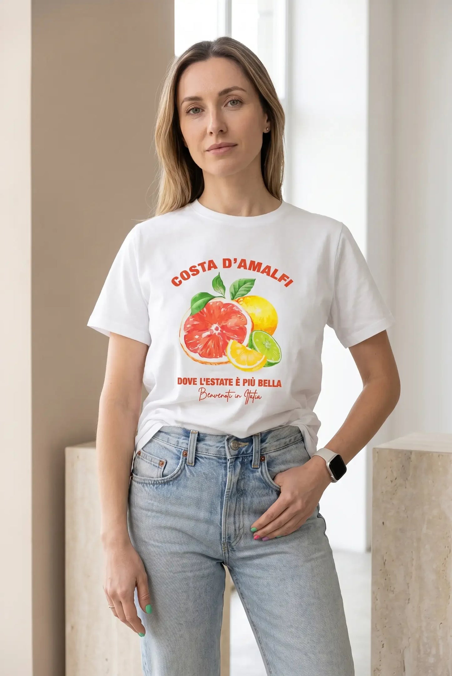 Mujer con camiseta blanca de estampado frutas Costa Amalfi y jeans claros, estilo casual femenino.