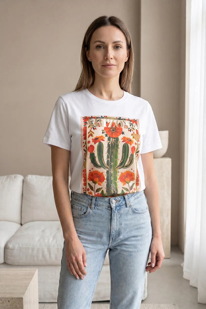 Mujer con camiseta blanca de manga corta, estampado de cactus y flores, y jeans claros