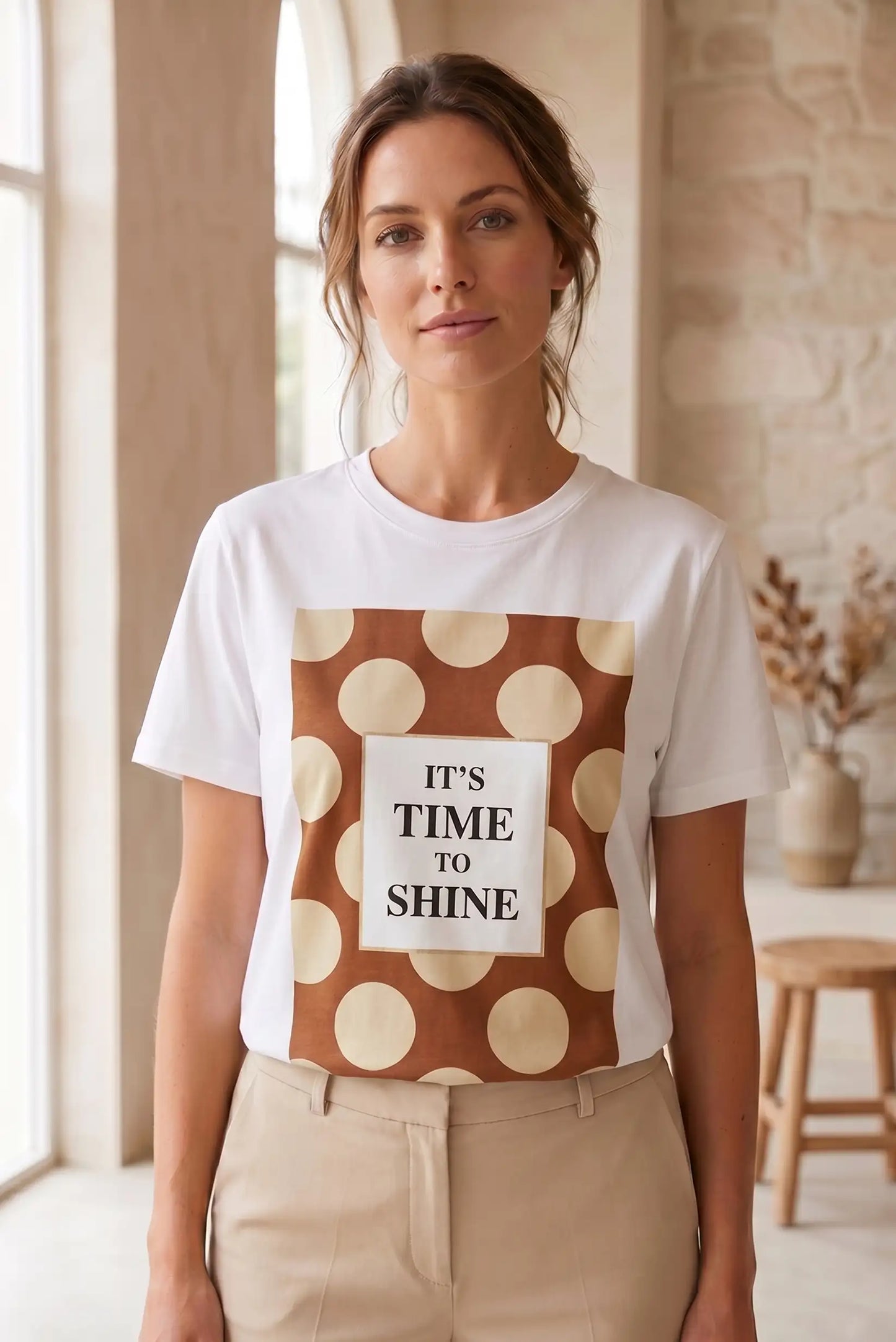 Mujer con camiseta blanca de manga corta, estampado de lunares beige y marrón, mensaje 'It's time to shine'.