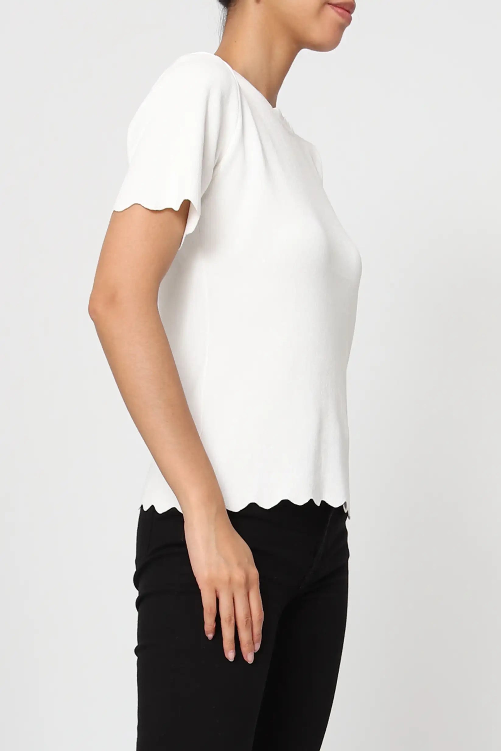 Mujer con camiseta blanca de manga corta y bordes ondulados, estilo casual de primavera.