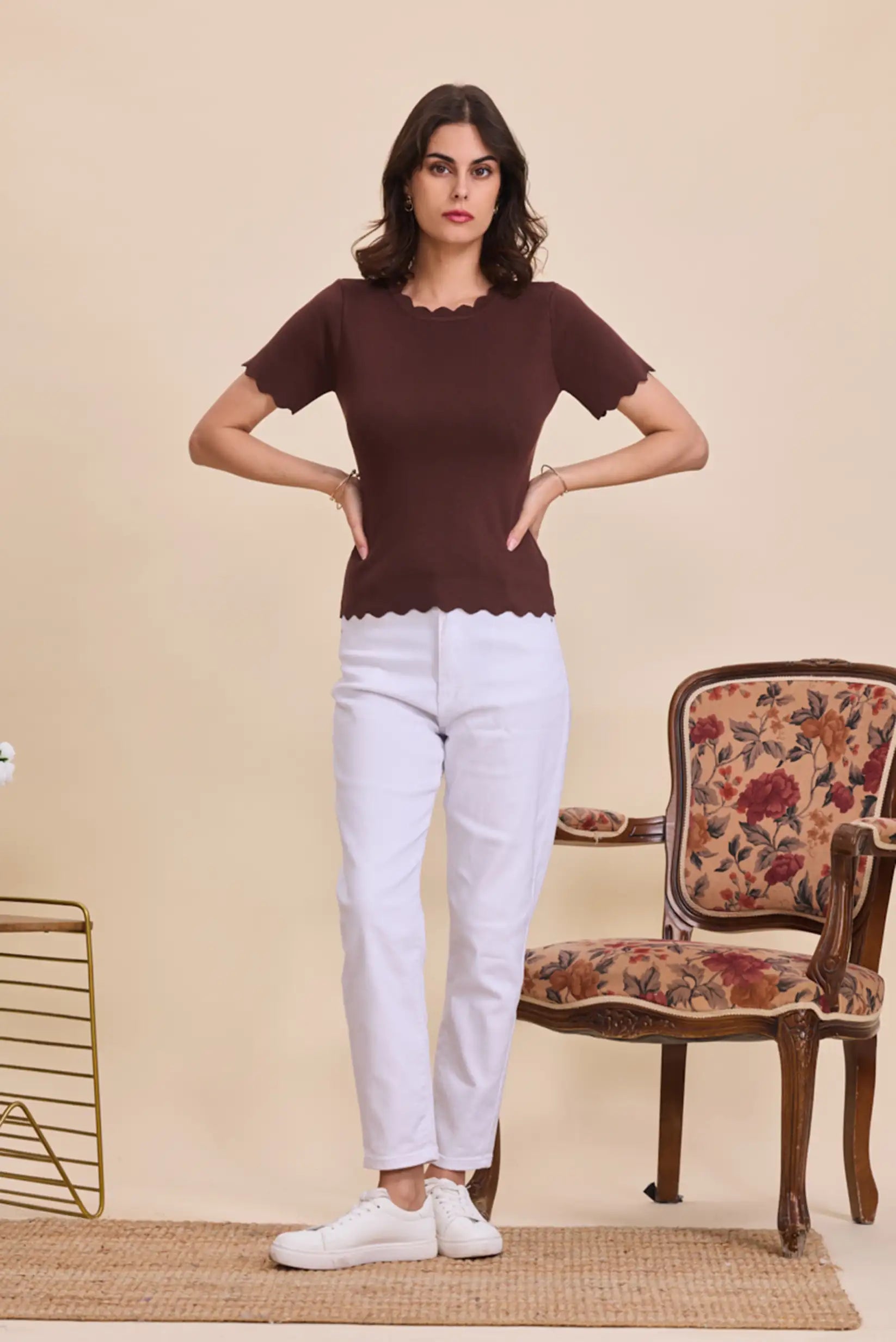 Mujer con camiseta marrón de manga corta y cuello ondulado, pantalón blanco y zapatillas blancas