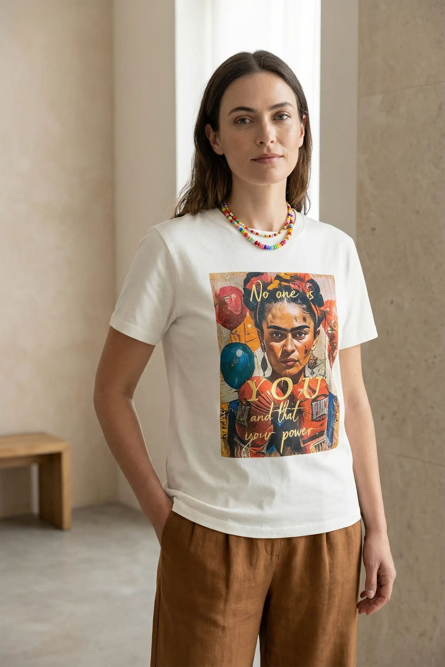 Mujer con camiseta blanca de manga corta con ilustración colorida de Frida Kahlo, moda casual.