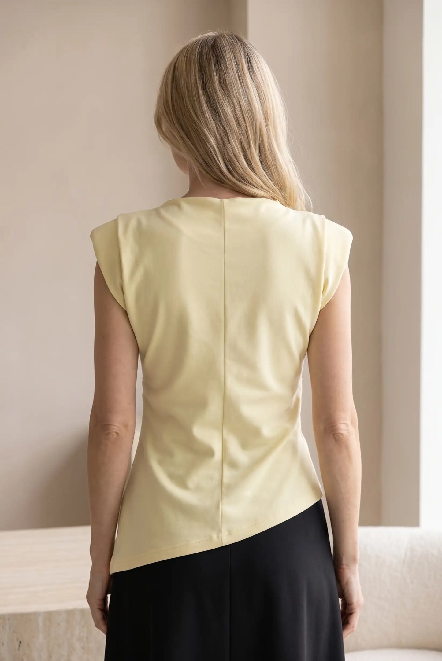 Mujer de espaldas con camiseta top asimétrica amarilla, estilo casual femenino