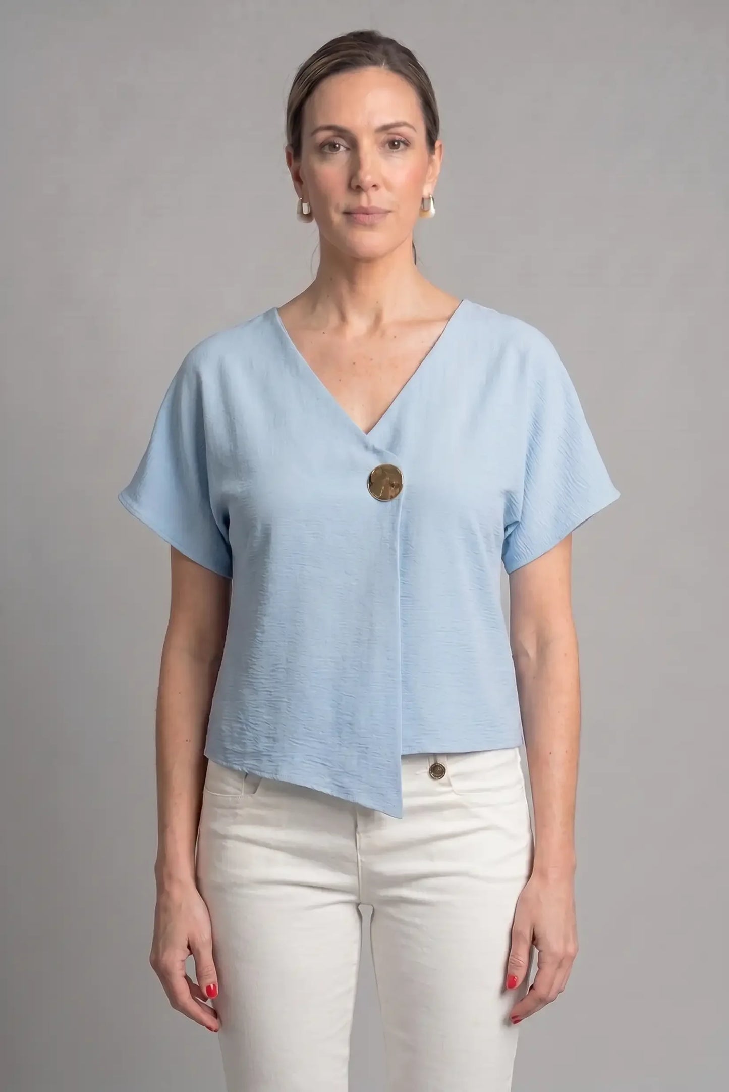 Mujer con camiseta azul cielo de manga corta y botón grande, look casual de primavera