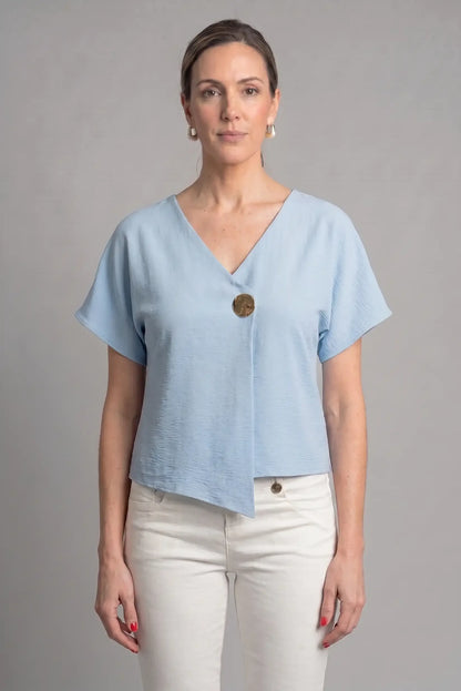 Mujer con camiseta azul cielo de manga corta y botón grande, look casual de primavera