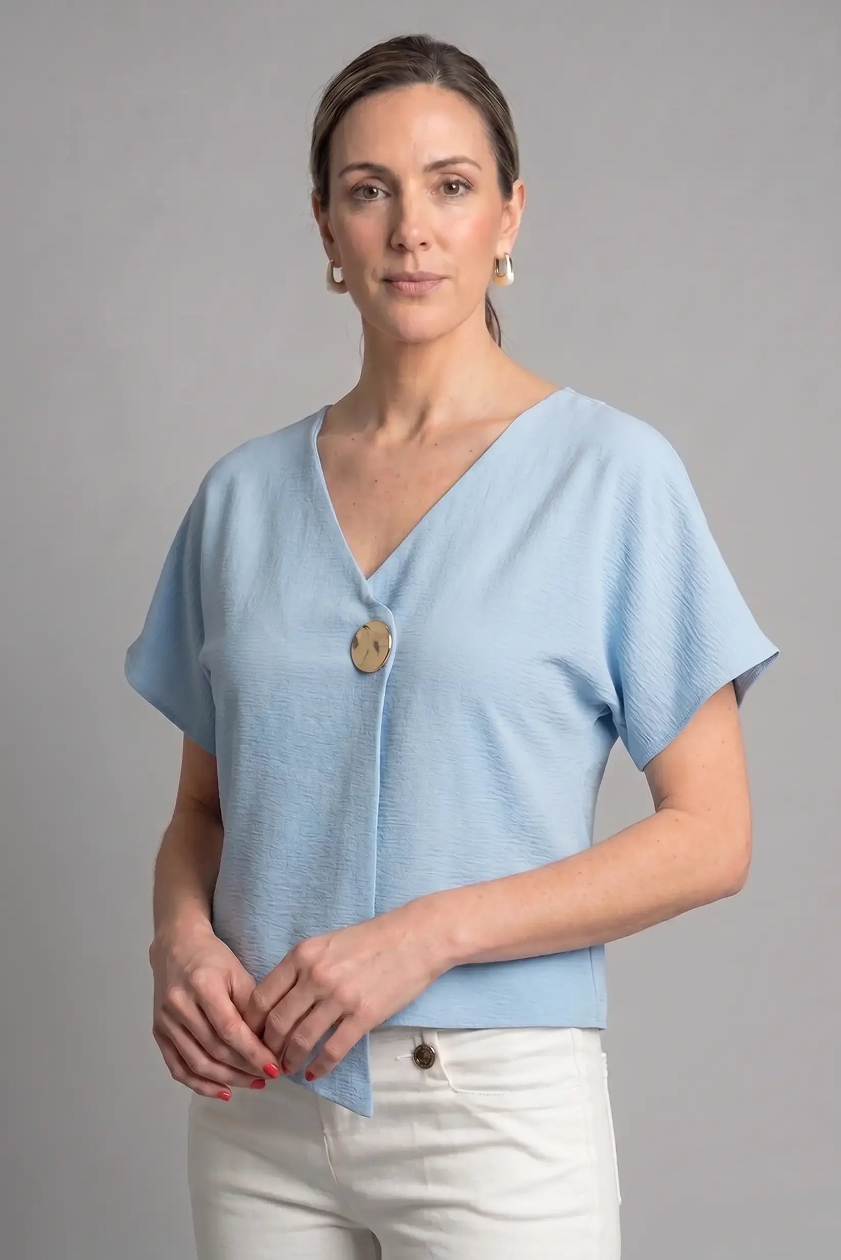 Mujer con camiseta azul cielo de manga corta y botón grande, look casual de primavera