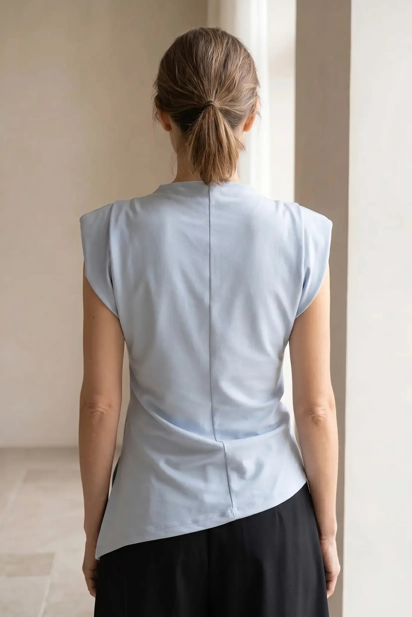 Camiseta top mujer azul celeste asimétrica de verano, vista trasera, sin mangas.