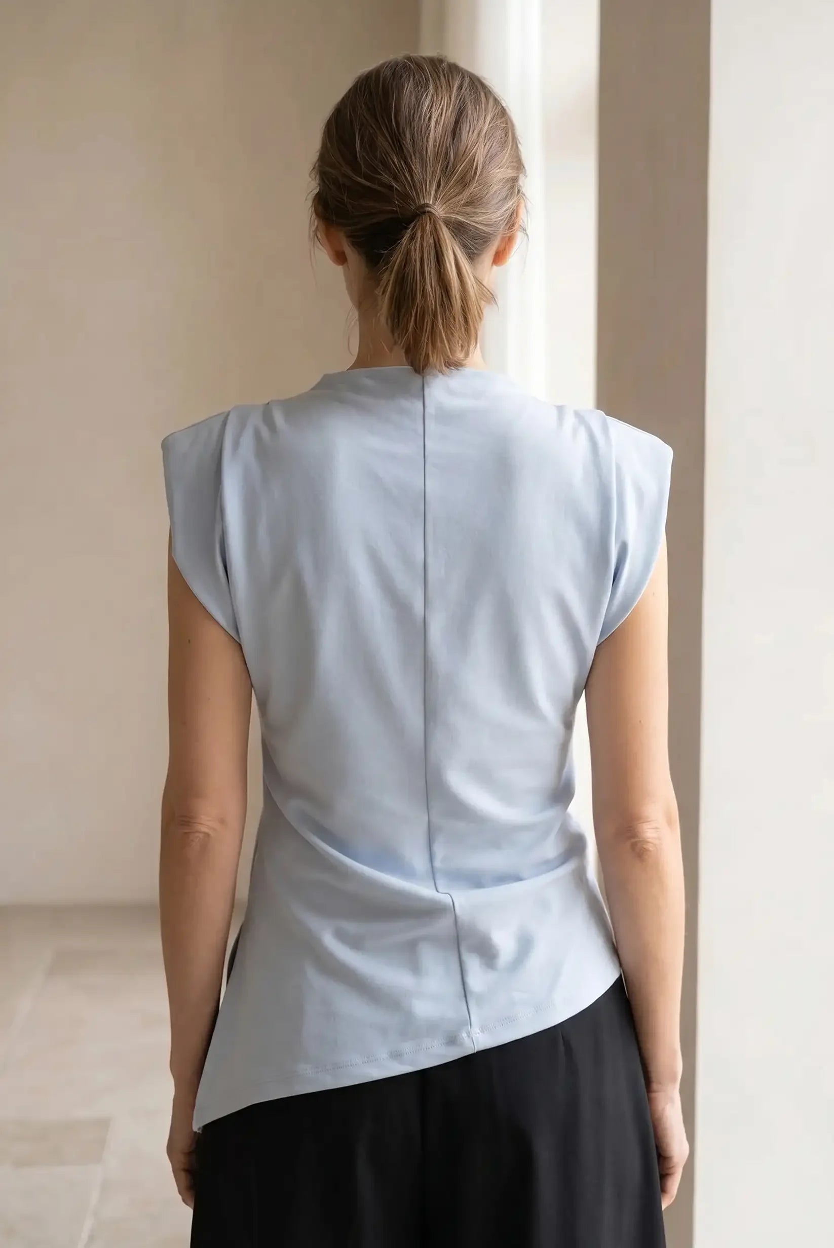 Camiseta top mujer azul celeste asimétrica de verano, vista trasera, sin mangas.