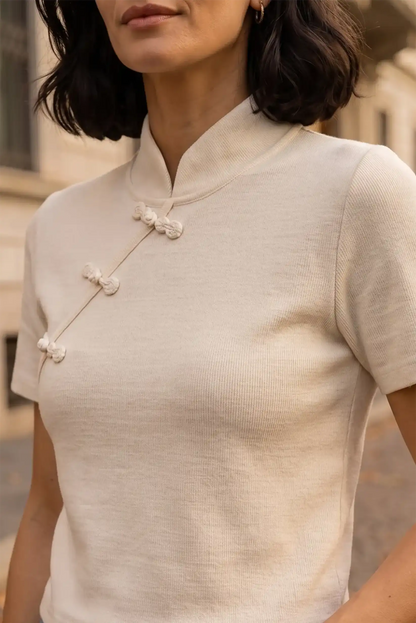 Camiseta blanca de manga corta con cuello mao y botones chinos decorativos.
