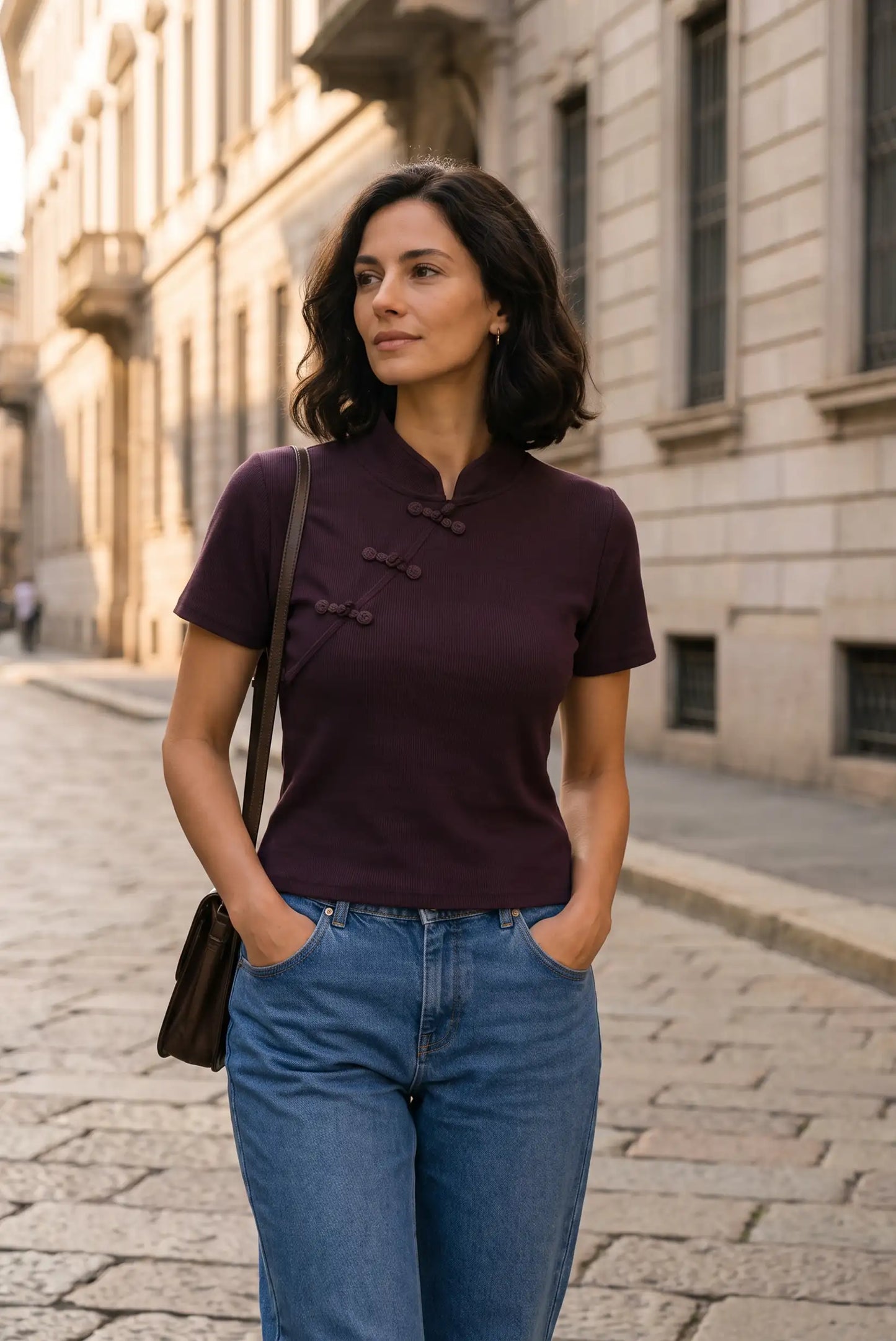 Mujer con camiseta ajustada color berenjena y vaqueros azules en una calle urbana.