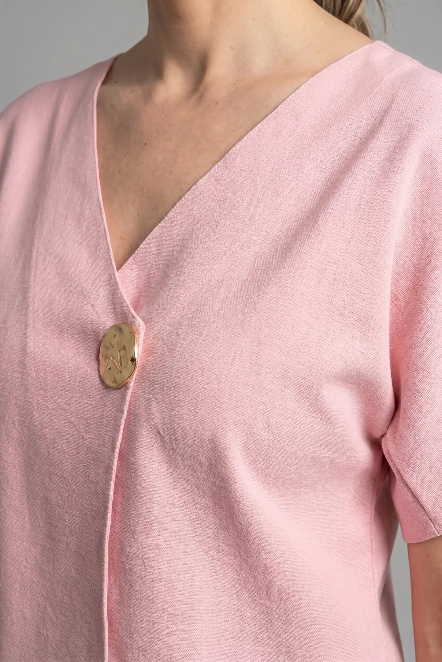 Camiseta top rosa de mujer con manga corta y escote en V, detalle botón dorado, moda primavera