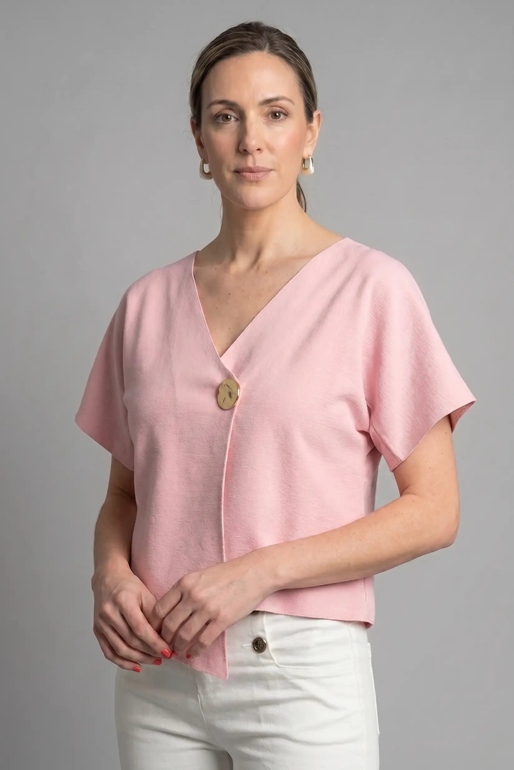 Mujer con camiseta rosa de manga corta y botón decorativo, look casual de primavera