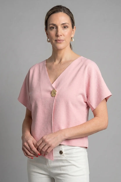 Mujer con camiseta rosa de manga corta y botón decorativo, look casual de primavera