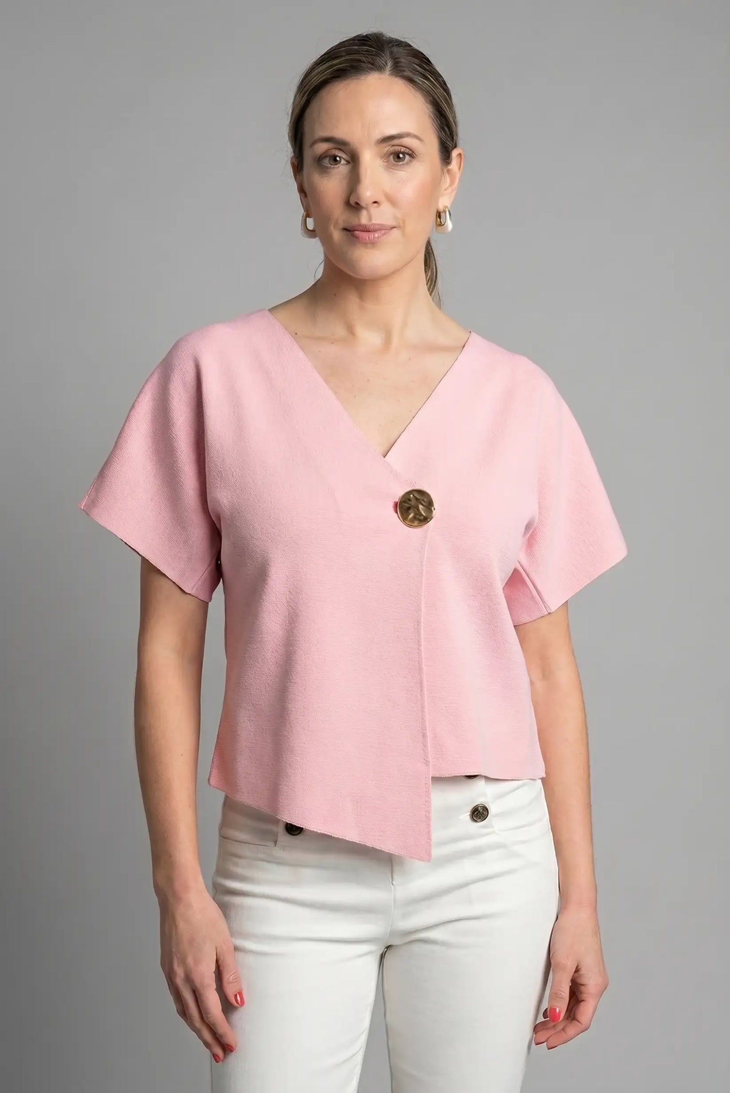 Mujer con camiseta rosa de manga corta y escote cruzado, detalle botón decorativo grande, moda casual