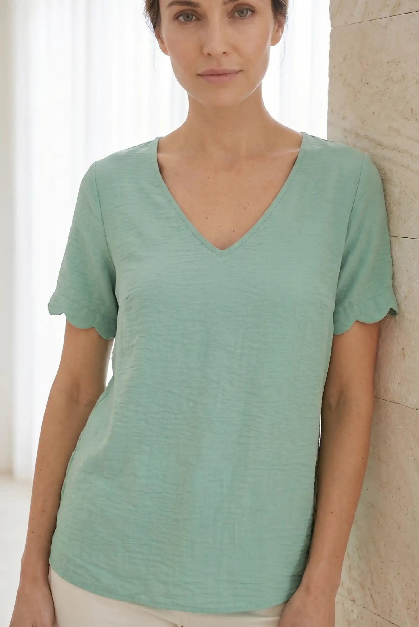 Camiseta verde menta con cuello en V y mangas con volante, ideal para looks casuales y cómodos.