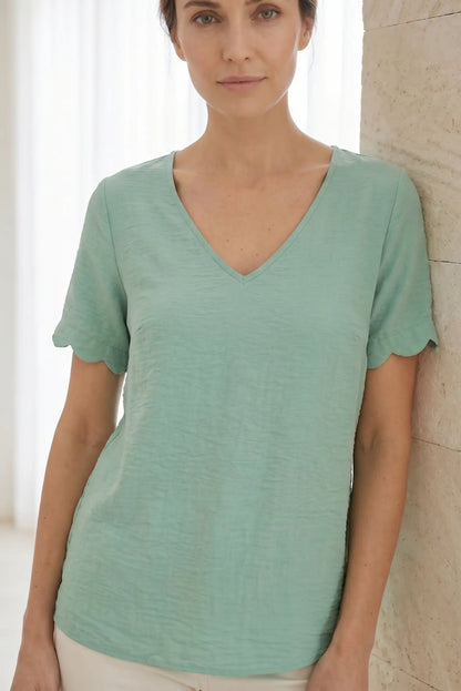 Camiseta verde menta con cuello en V y mangas con volante, ideal para looks casuales y cómodos.