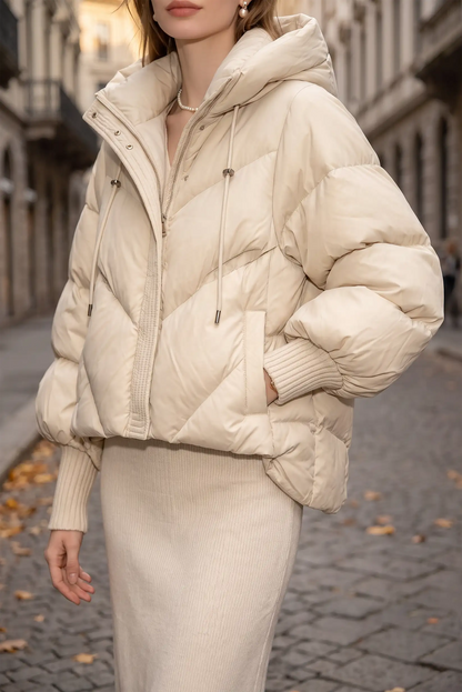 Mujer vistiendo una chaqueta acolchada color crema con capucha y falda a juego.