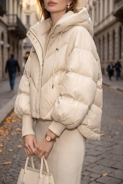 Mujer vistiendo una chaqueta acolchada corta color crema con capucha y falda midi a juego.