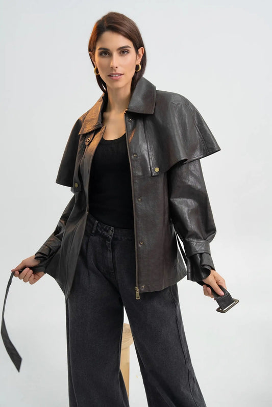 Mujer vistiendo chaqueta de cuero negra con diseño asimétrico y pantalones anchos oscuros.